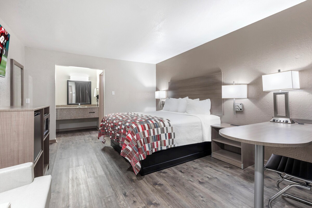 Una habitación de hotel con cama, mesita de noche y un pequeño escritorio.