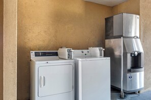 A commercial laundry area with a front-loading washer, a dryer, and a water dispenser. - Red Roof Inn Canton, TX (Canton)