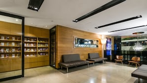 A modern Starbucks Coffee store with seating areas, bookshelves, and a large sign. - Nathan Hotel (Kowloon)