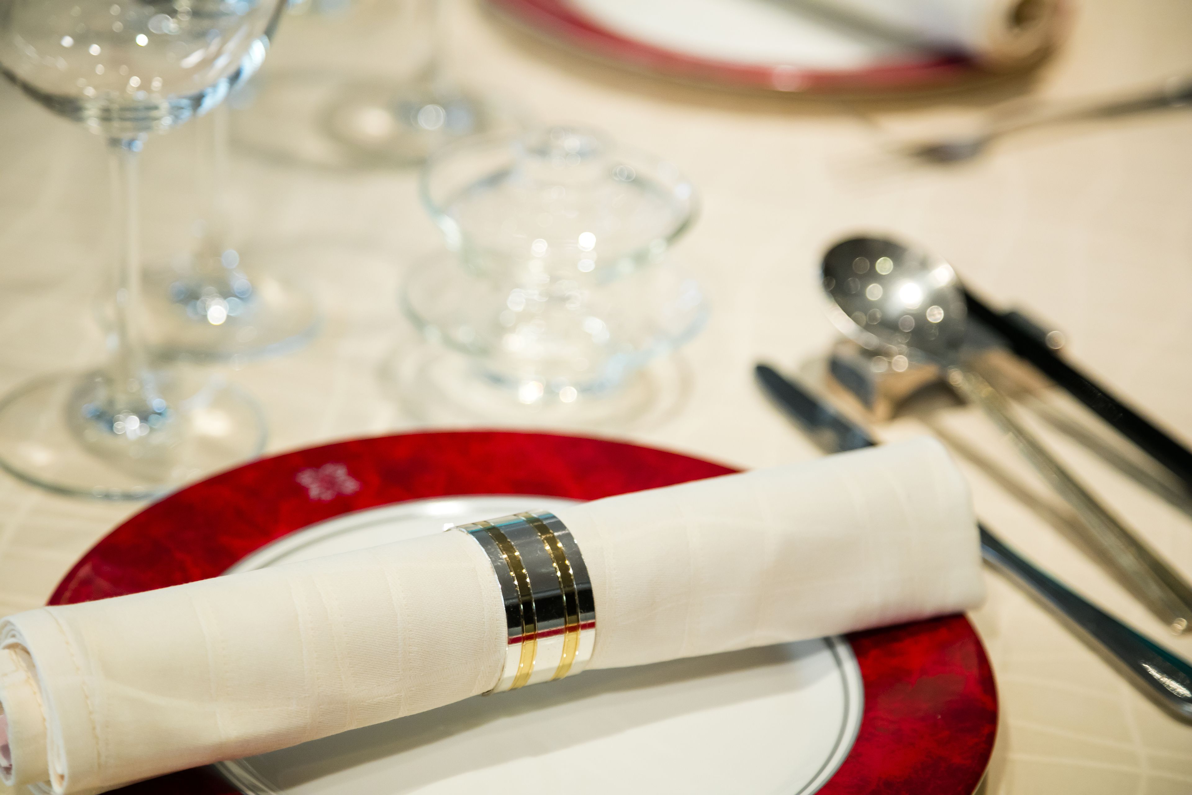 A table setting with a red plate, a folded napkin, and silverware.