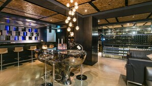 A modern bar area with a unique metallic centerpiece, a wine display, and contemporary seating. - Nathan Hotel (Kowloon)