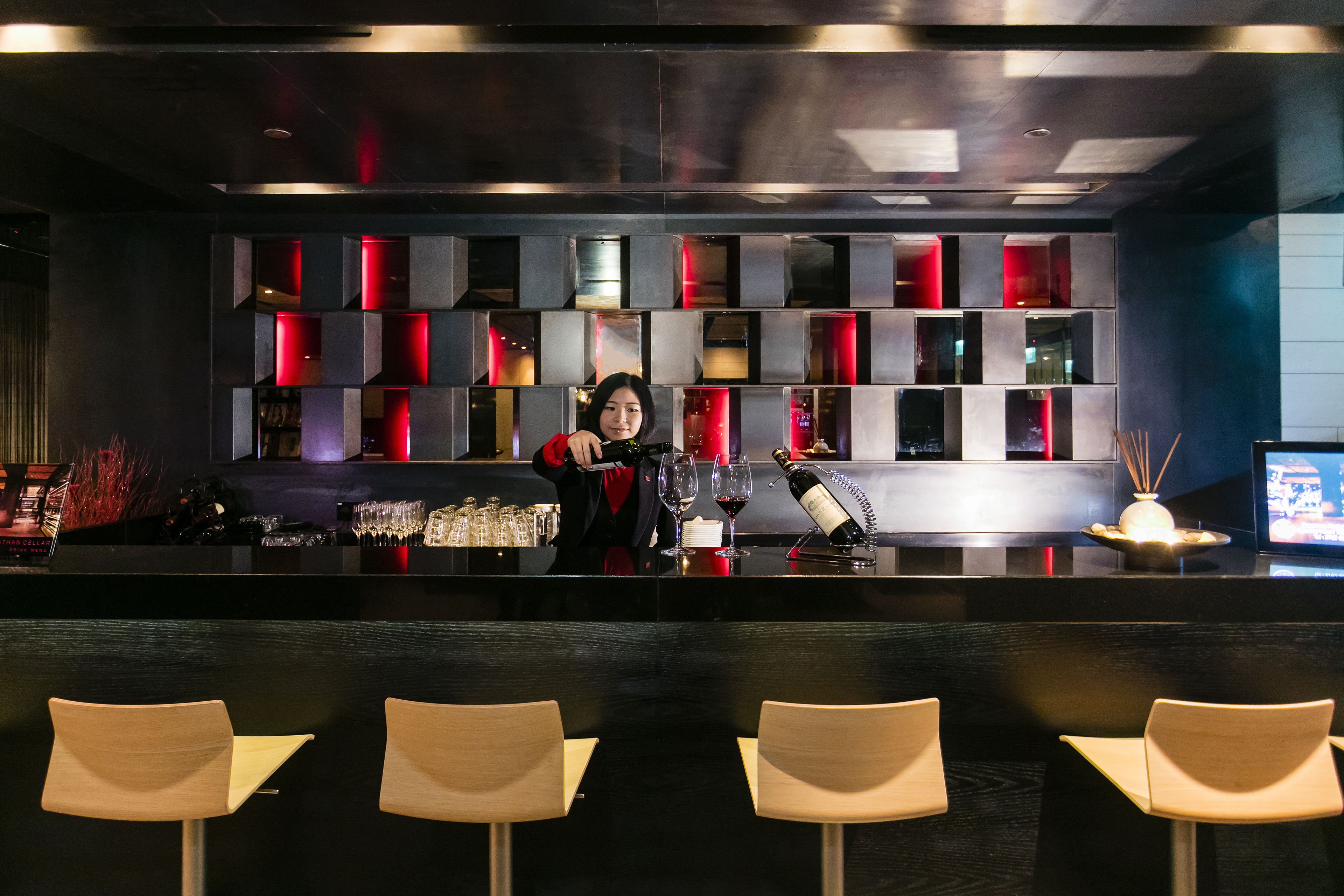 A bar area with a bartender, bar counter, and seating.