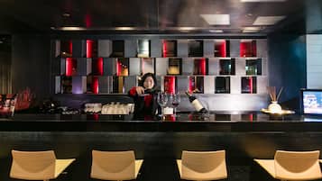 A bar area with a bartender, bar counter, and seating.