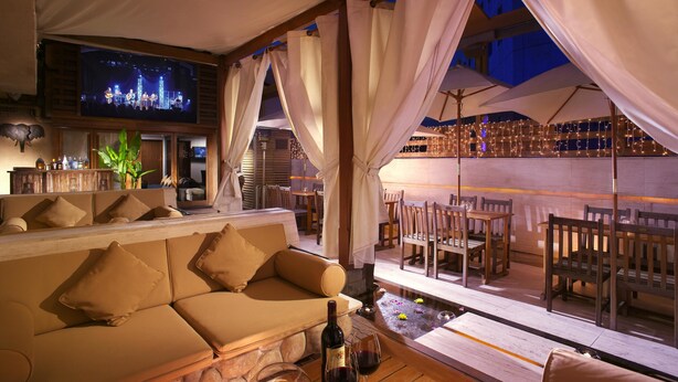 A cozy lounge area with a sofa, wooden tables, and a bar with a TV screen. - Nathan Hotel (Kowloon)