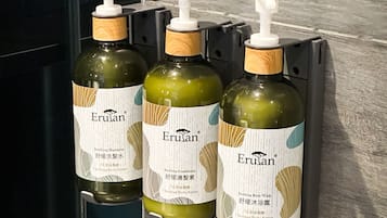 Three Erulan bottles of soothing shampoo and conditioner on a black surface.