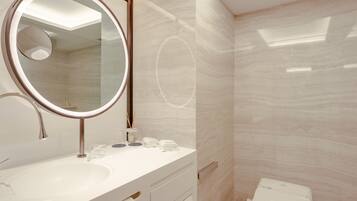 A modern bathroom with a round mirror, a sink, a toilet, and a skylight.