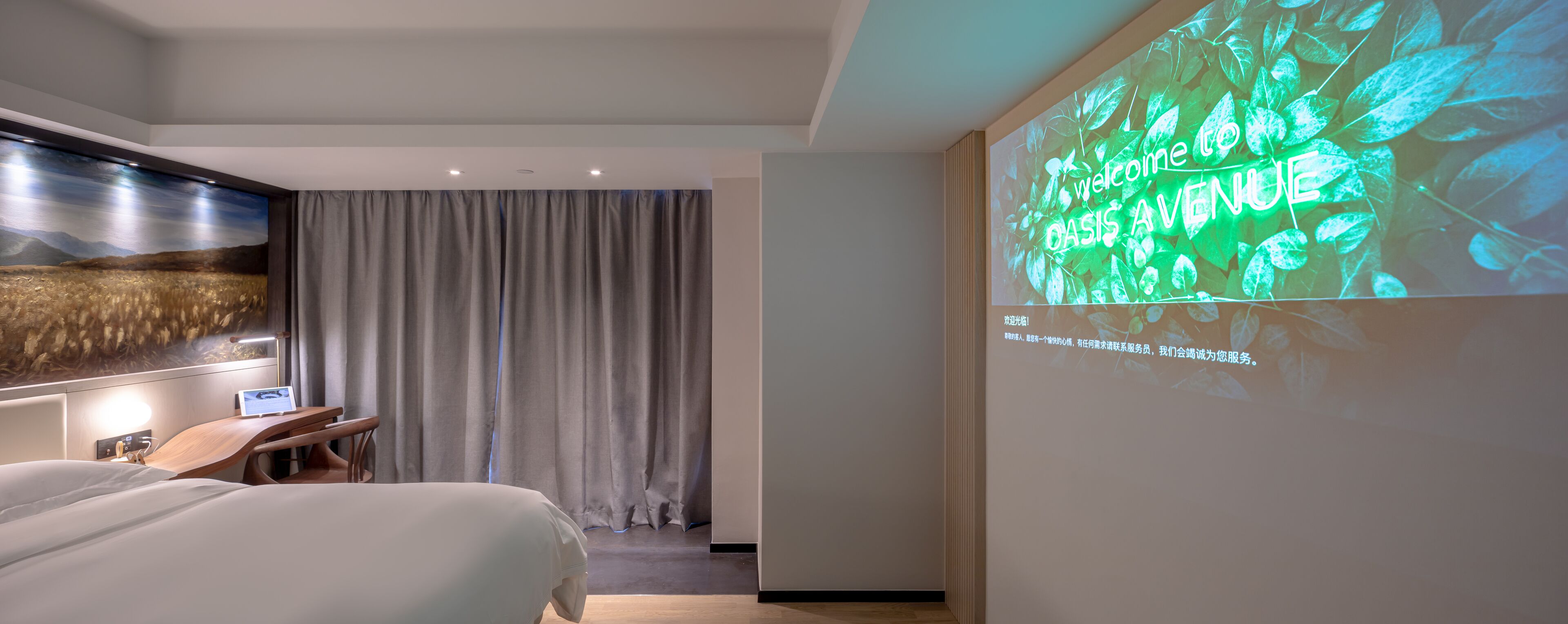 A hotel room with a bed, a desk, a TV, and a projection screen displaying a welcome message.