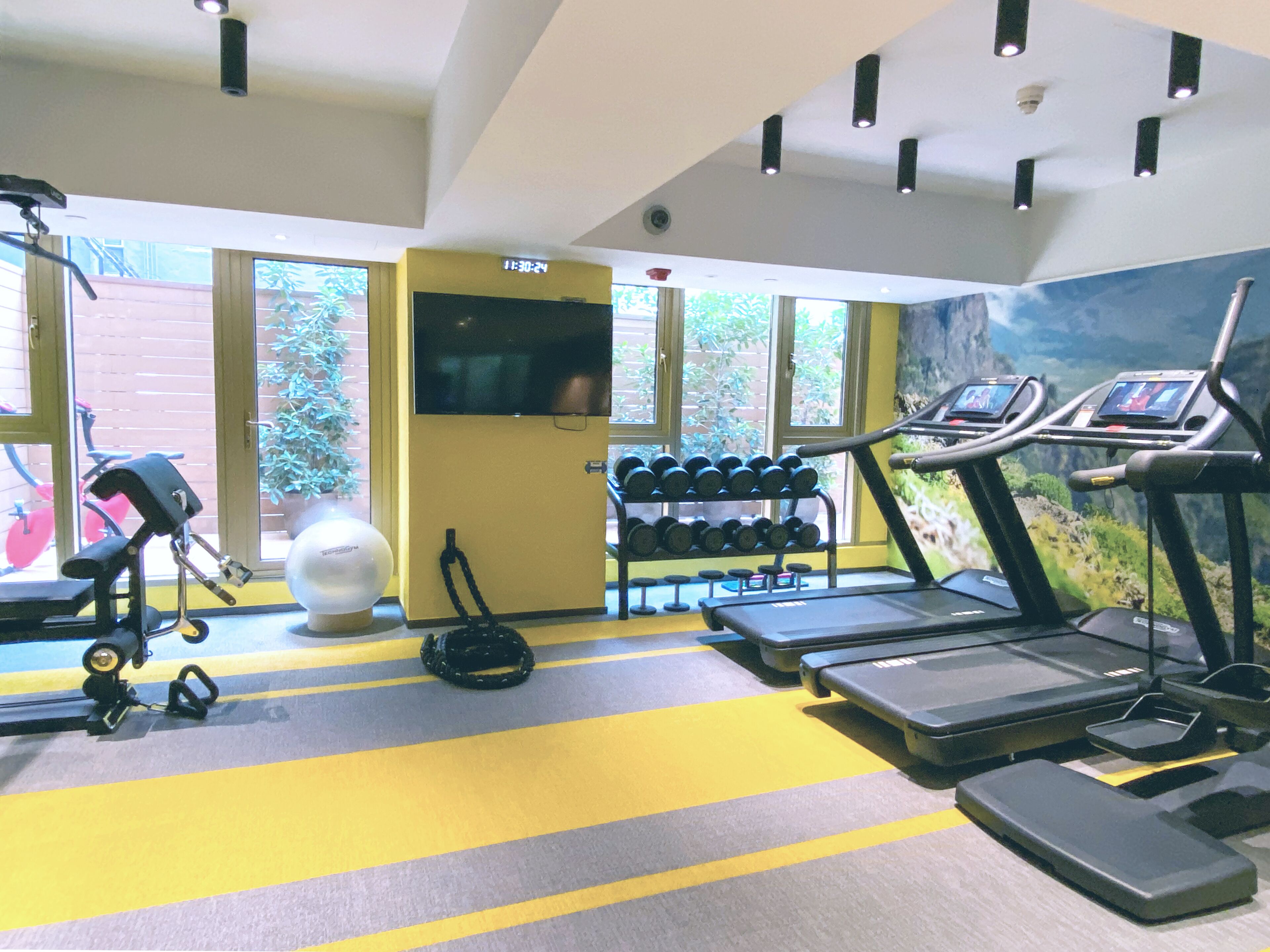 Une salle de sport équipée de tapis de course, d’haltères et d’autres appareils d’exercice.