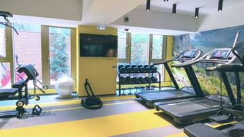Une salle de sport équipée de tapis de course, d’haltères et d’autres appareils d’exercice.