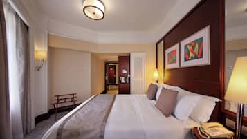 Una camera d'albergo con un letto rifatto, un comodino con una lampada, un telefono e un'opera d'arte incorniciata appesa al muro.
