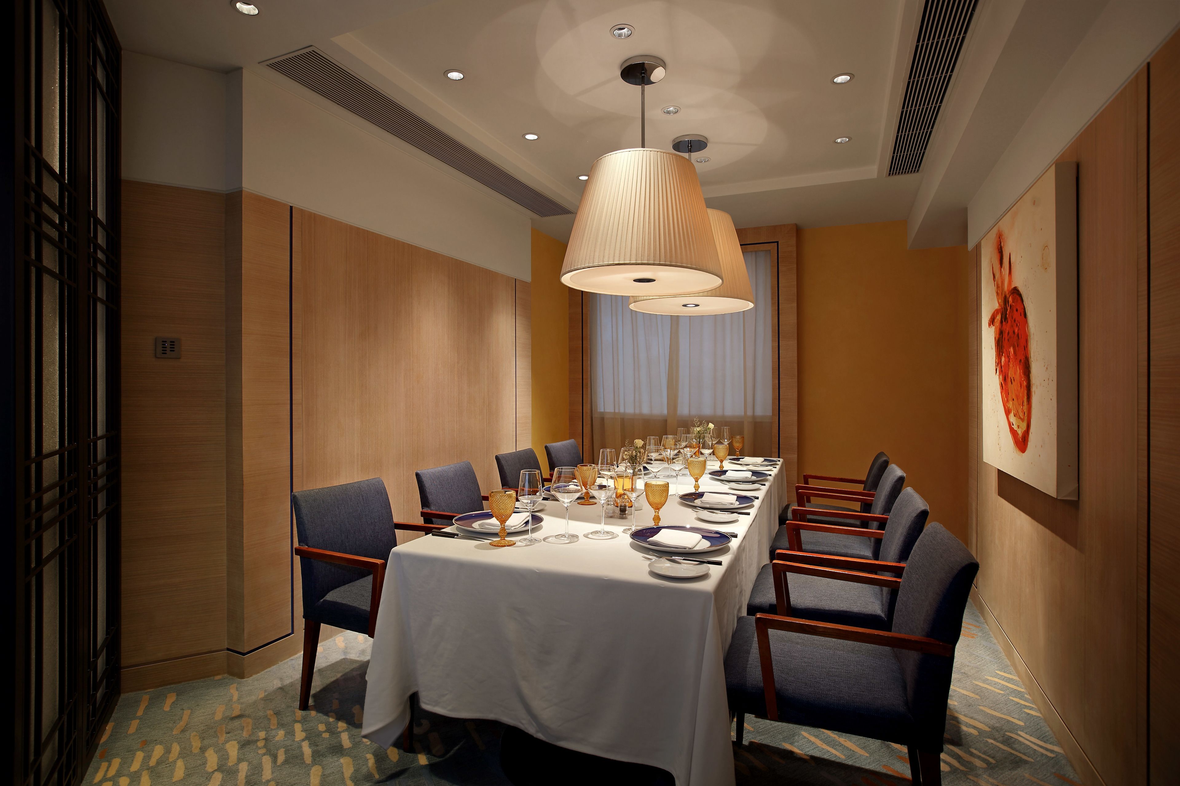 Comedor con una mesa larga dispuesta para una comida, rodeada de sillas.