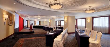 A conference room with a long table, chairs, and a stage.