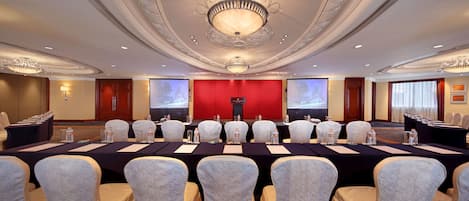 A conference room with a long table, chairs, and a screen at the front.