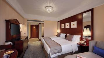 Une chambre d’hôtel avec deux lits, une télévision, un bureau avec une machine à café et un miroir.