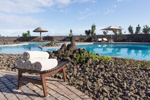 Una piscina al aire libre, sombrillas, tumbonas