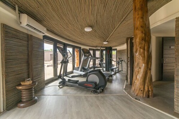 A gym with exercise equipment, wooden ceiling, and large windows.