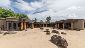 Un resort frente a la playa con varias habitaciones tipo bungalow, cada una con entrada privada y una playa de arena frente a ellas.