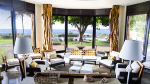 Un espacio lounge moderno con vista al océano, que incluye un conjunto de sofás, dos lámparas y una mesita de centro.