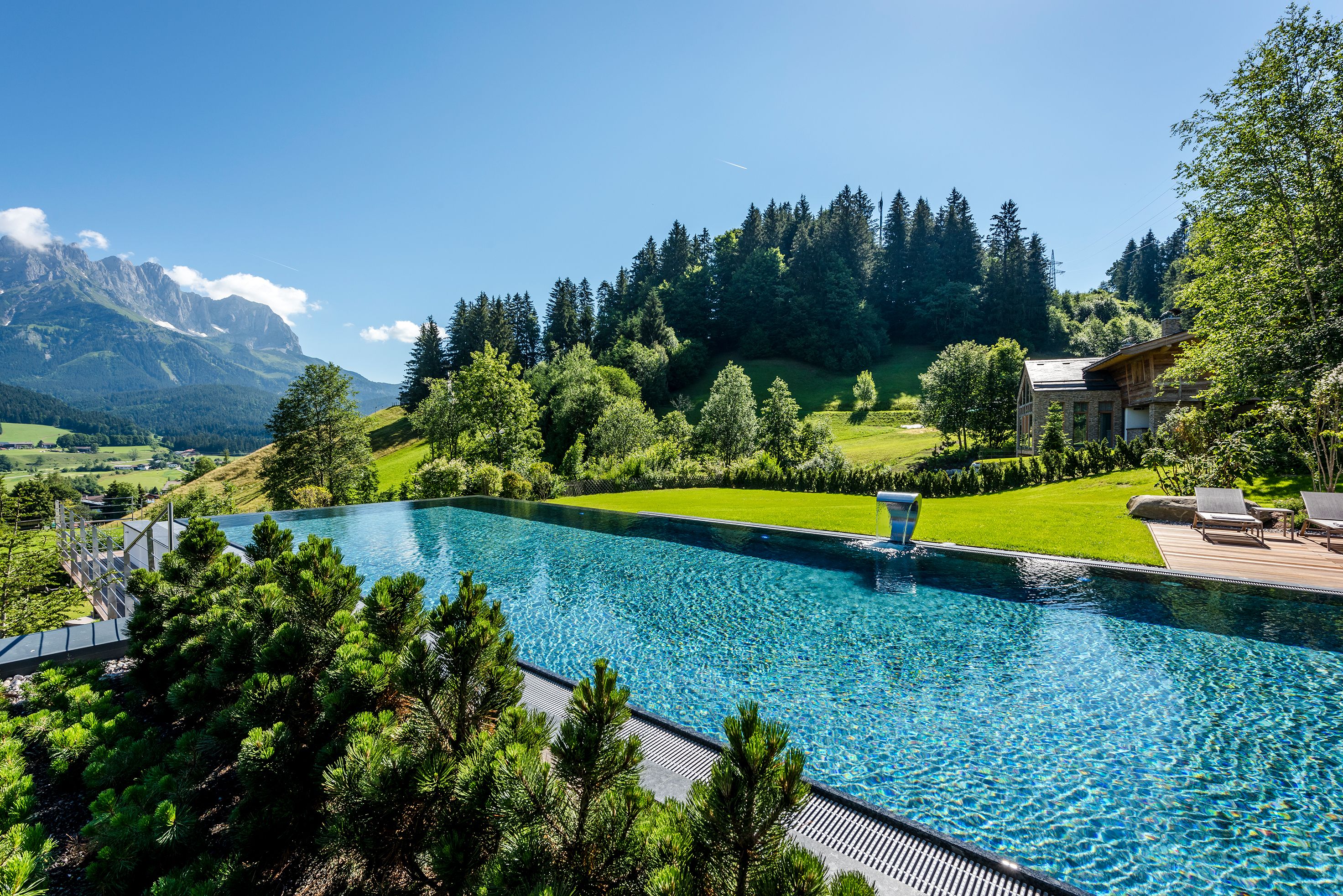 Une piscine avec vue sur les montagnes et une pelouse bien entretenue.