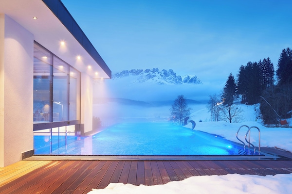 Una piscina cubierta, una piscina al aire libre, sombrillas, tumbonas