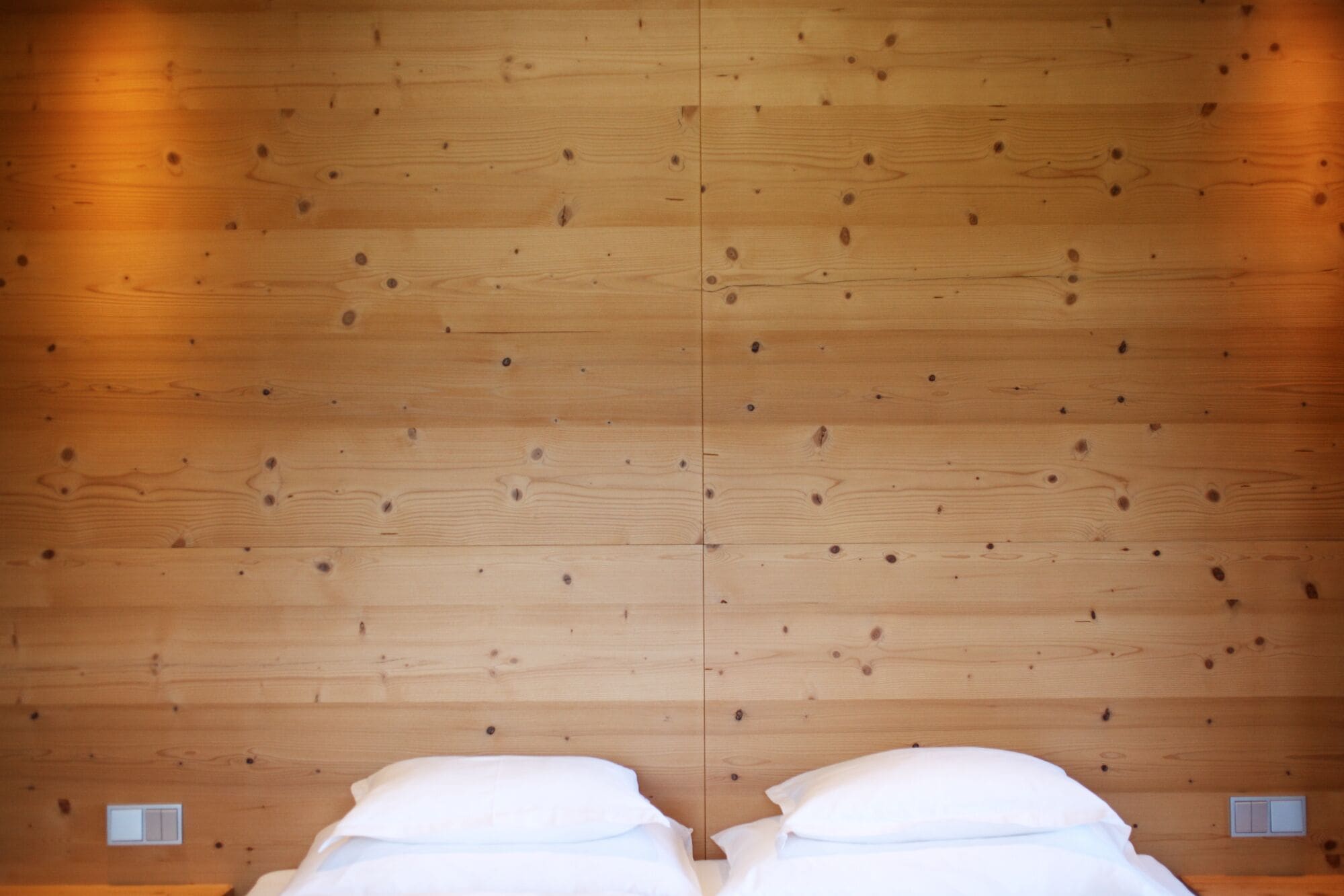 A room with wooden panel walls and a bed with white bedding.