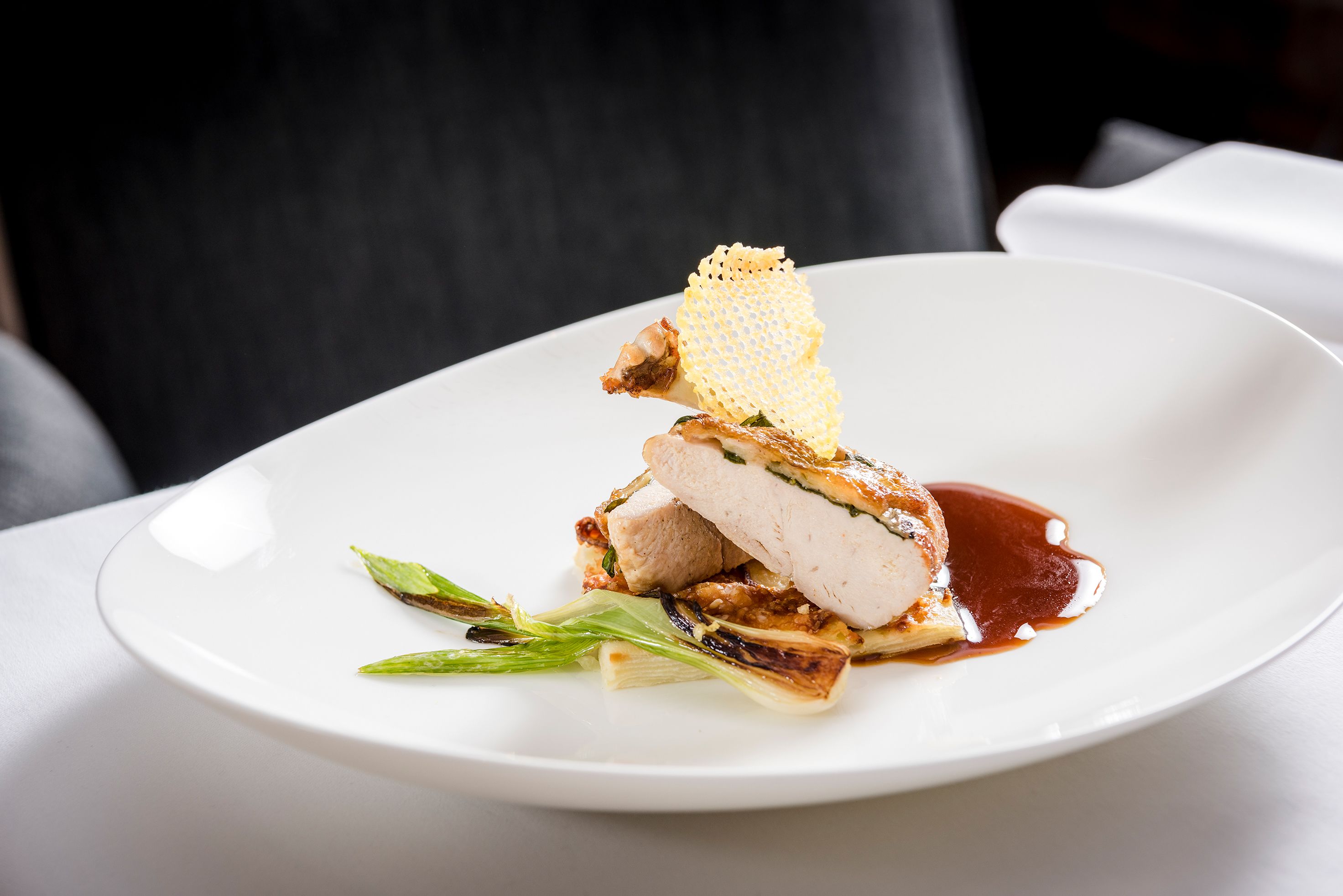 Une assiette blanche contenant un morceau de viande, une tranche de pain et quelques légumes verts.
