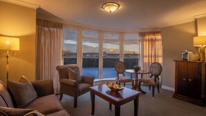 A hotel room with a large window, a sofa, a table, and a cabinet. - Bracken Court Hotel (Balbriggan)