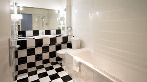 A bathroom with a checkered floor, a white bathtub, a toilet, and a sink with a mirror above it. - Hôtel Raymond 4 Toulouse (Toulouse)