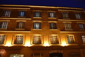 Traditional European-style building with a brick facade and multiple windows, featuring balconies with railings.