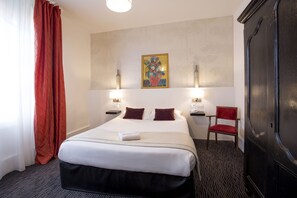 Comfortable room with a neatly made bed, a chair, and a painting on the wall, featuring two bedside tables with lamps and a wardrobe.