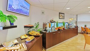 Una zona de recepció amb un mostrador de buffet, un televisor que mostra informació de l'hotel i un rellotge a la paret.