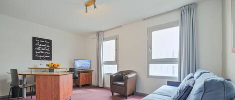 A room with a bed, a desk, a chair, and a television.