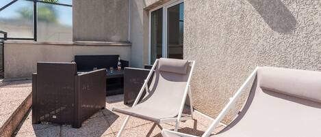 An outdoor seating area with wicker furniture and a glass balustrade.