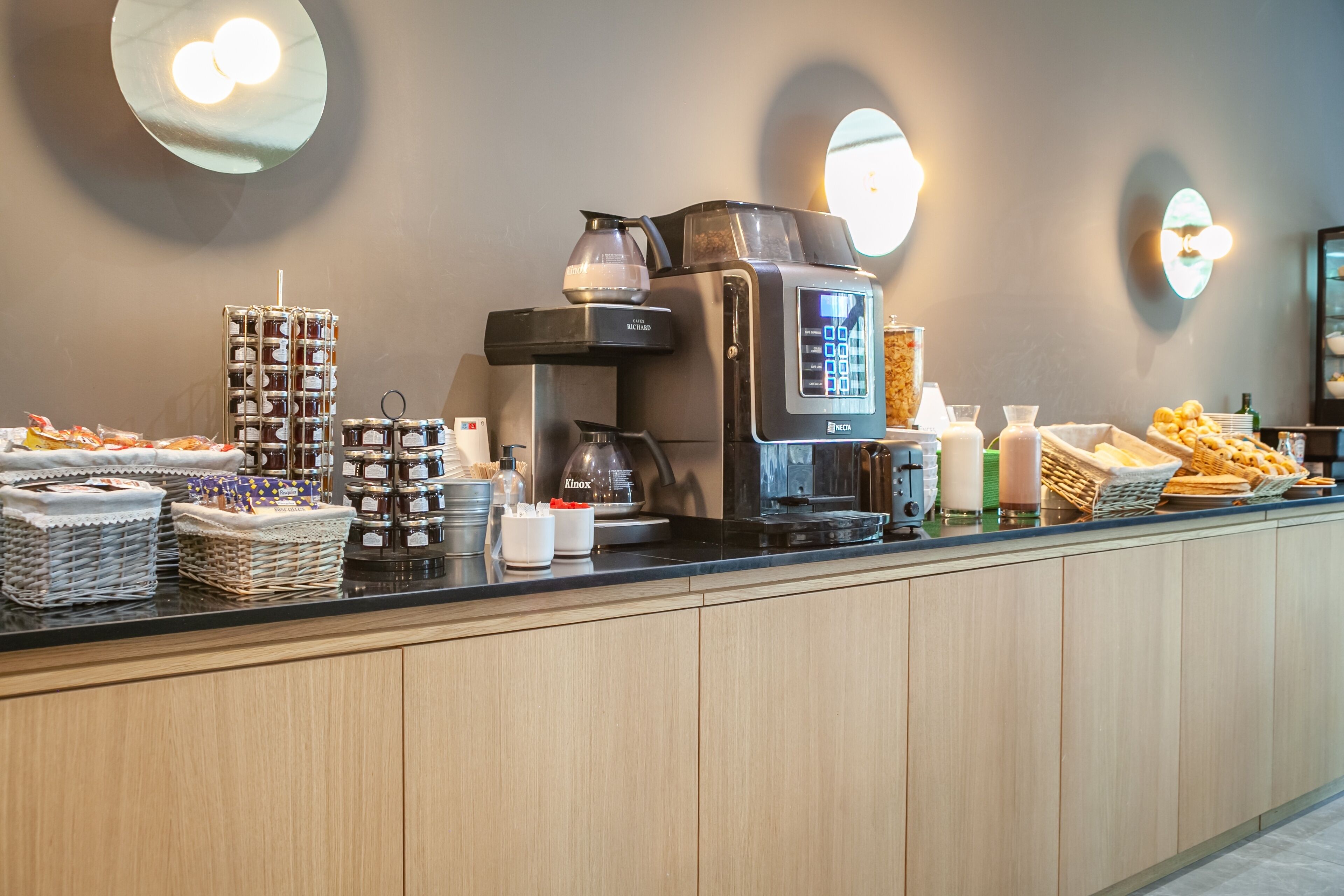 A buffet counter with a coffee machine, various food items, and condiments.