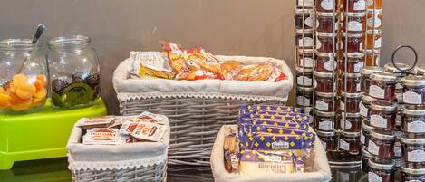 A variety of food items including jars of honey, packets of biscuits, and bags of snacks.