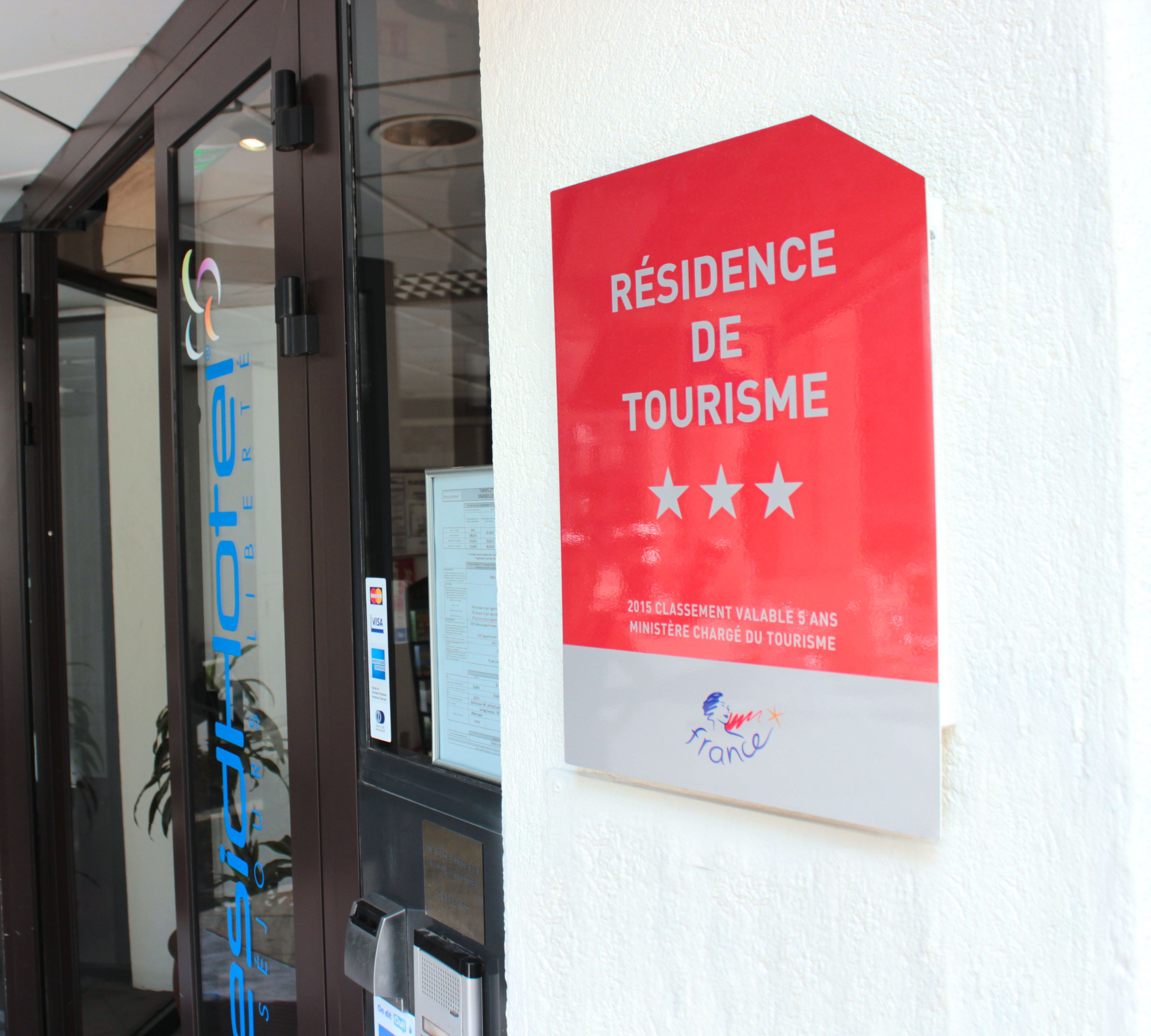 A hotel entrance with a sign reading "RESIDENCE DE TOURISME" and a logo for France.