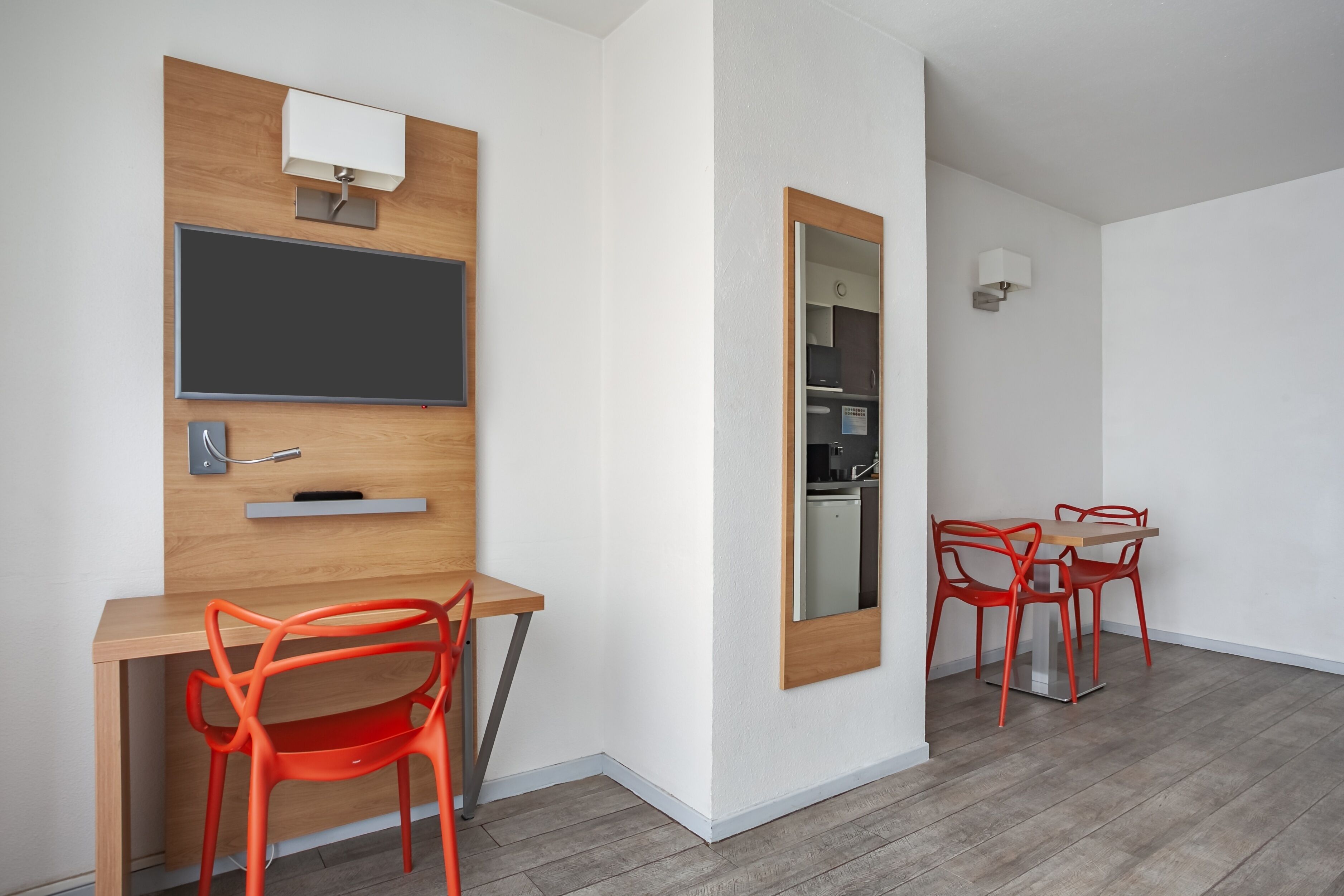 Quarto moderno com escrivaninha de madeira, uma cadeira, espelho e mesa de jantar com cadeiras.