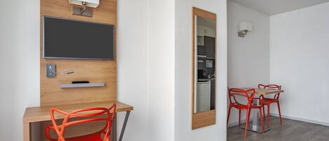 Una habitación moderna con un escritorio de madera, una silla, un espejo y una mesa de comedor con sillas.