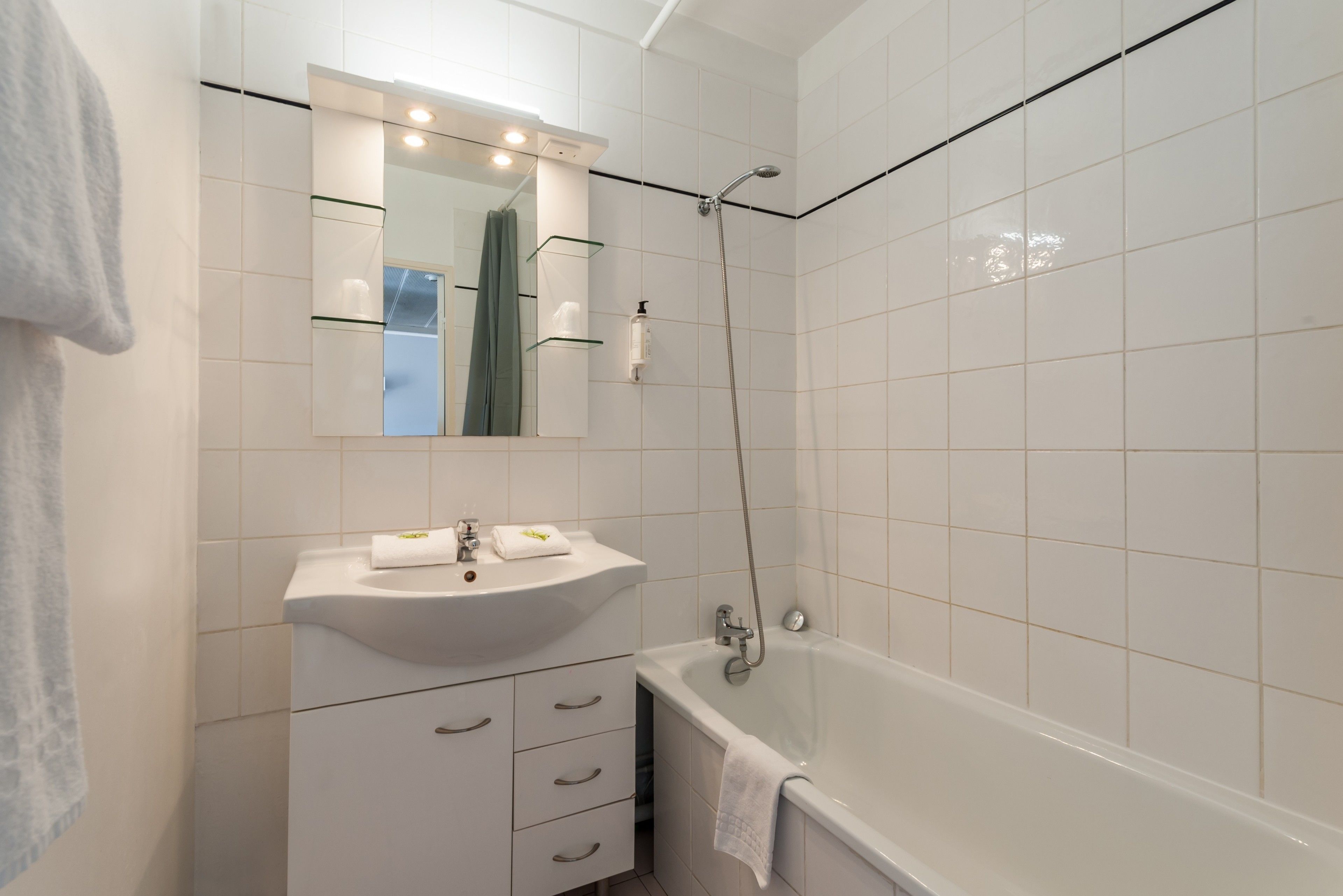 Un baño con lavamanos blanco, espejo y bañera.