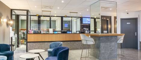 A modern reception area with a marble counter, blue velvet chairs, and a glass partition.