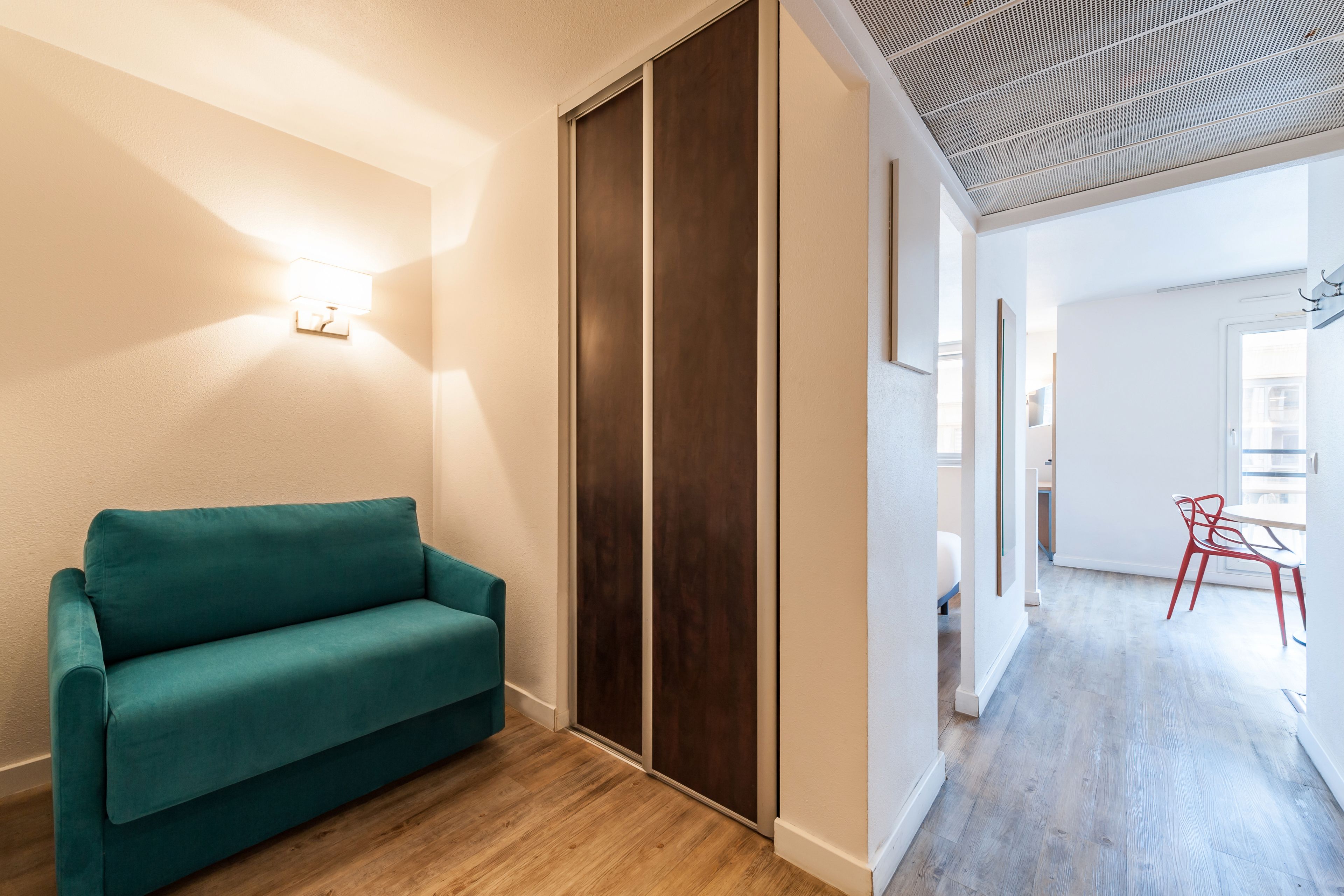 Un interior moderno con un sofá color turquesa, suelo de madera y un techo con diseño de cuadrícula.