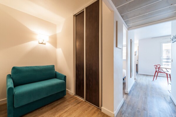 A modern interior with a teal sofa, wooden flooring, and a ceiling with a grid pattern. - Residhotel Grand Prado (Marseille)