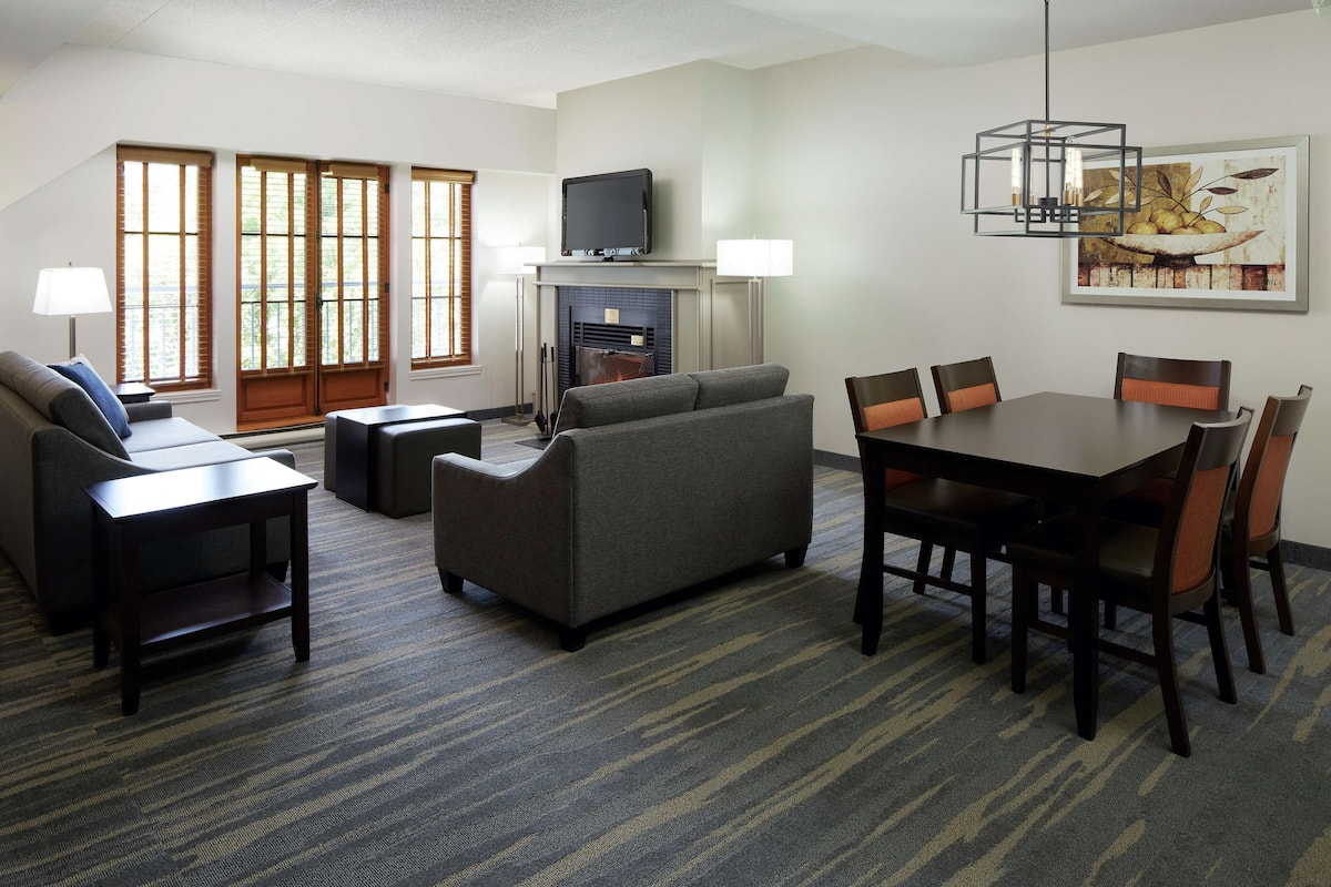 A modern living room with a fireplace, a flat-screen TV, a dining table with chairs, and a sofa.