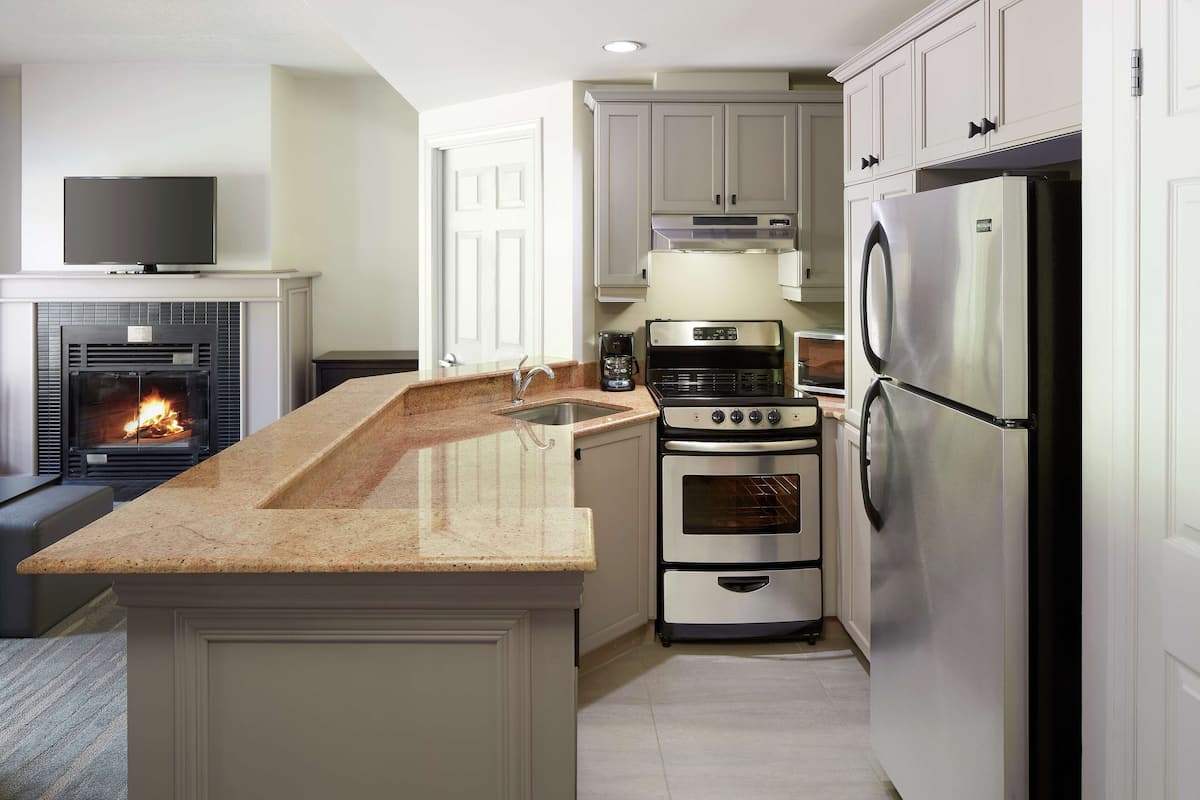 A modern kitchen with a built-in oven, a refrigerator, and a coffee maker.