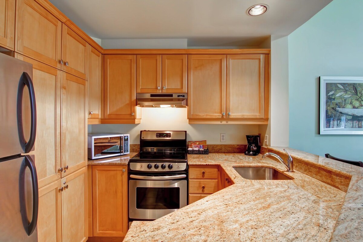 A kitchen with wooden cabinets, a stainless steel stove, a microwave, and granite countertops.