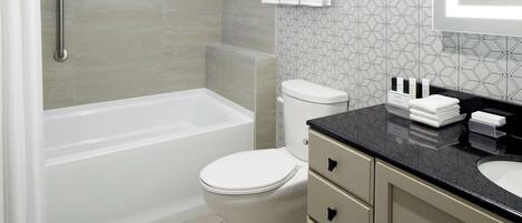 Un baño moderno con bañera, inodoro y tocador con lavabo.