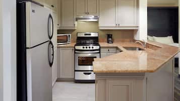 Cocina compacta con refrigerador, microondas, estufa, horno y encimera de granito.
