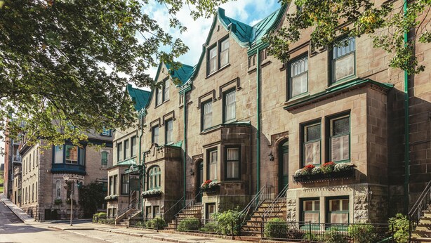 A row of historic stone buildings with green trim and dormer windows.
