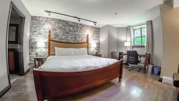 Una habitación de hotel moderna con una cama de madera, pared de piedra, escritorio y silla.