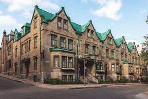 Un edificio histórico de varios pisos, con techos de tejas verdes y una entrada destacada con escalones.